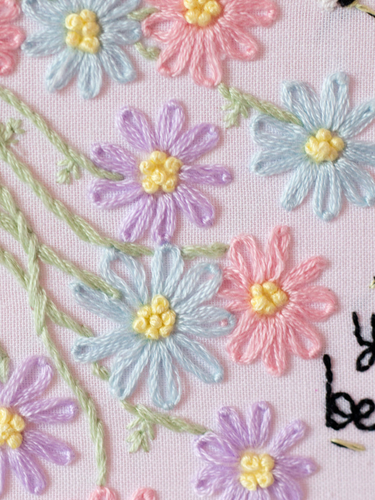 White fabric with hand embroidery stitching pastel flowers, and you are beautiful text.