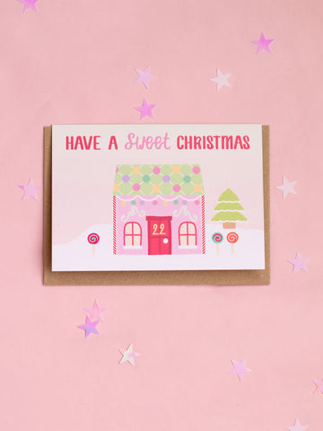 A Christmaa card with a pastel candy house and 'Have A Sweet Christmas' written on top.