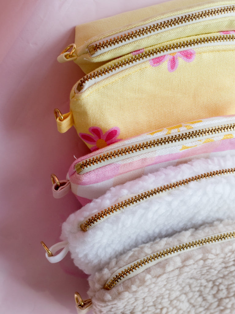 A top view of five different coloured coin purses on a pink-marbled floor. 