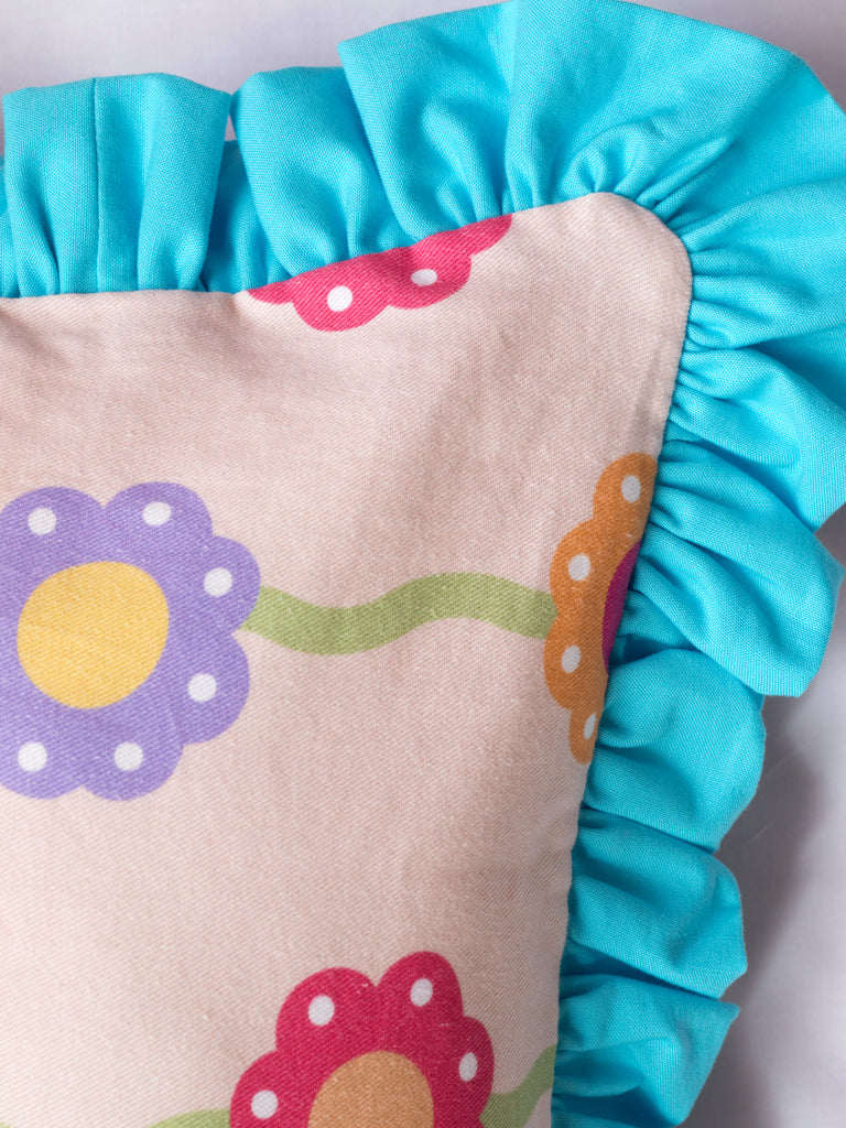 A close-up of a pink floral printed cushion shows the blue ruffle details.