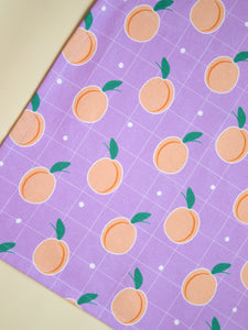 A purple tea towel with peaches printed onto it