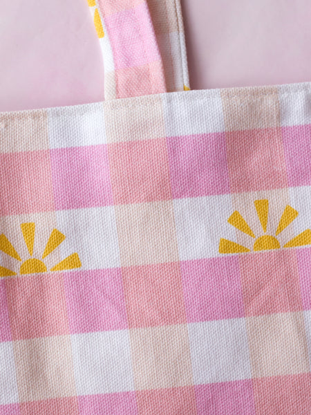 Close-up details of a pink gingham tote bag with sunshine prints.