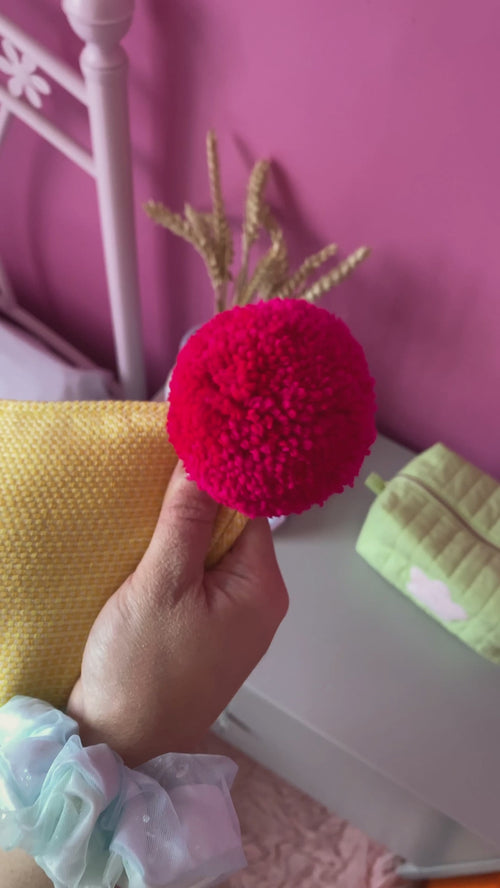 A yellow textured cushion with bright pink pom-poms is opened by the concealed zip and shows close-ups of fabric details.