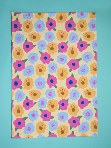 a yellow tea towel with colourful flowers on an aqua background.