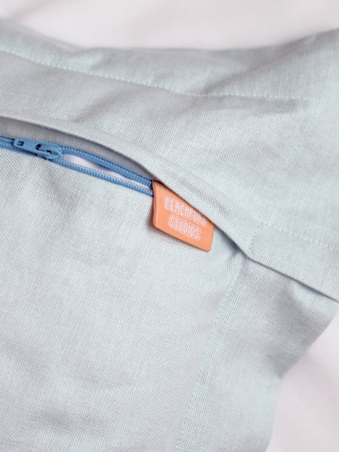 A close-up of a light blue cushion cover shows the back zip detail.