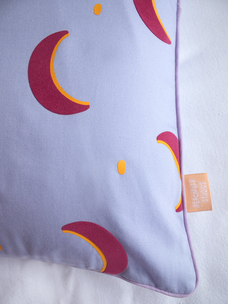 A close-up of a lilac cushion cover shows the pink and yellow vinyl crescent moons and piping details.