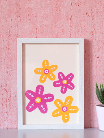 A framed art print of two orange and two pink flowers in front of a pink textured wall.