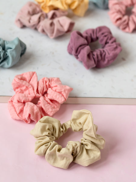 `different coloured pastel scrunchies are placed next to each other on a terrazzo and pink tabletop. 