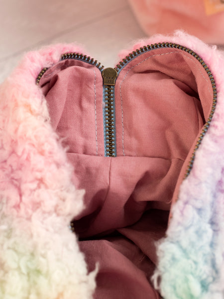 A close-up detail of rainbow fluffy makeup bag with a pink lining.