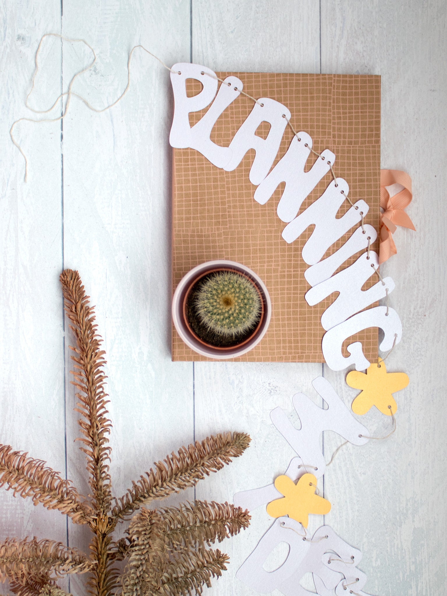 A paper garland unravelled on a white wooden floor that reads 'Planning'.