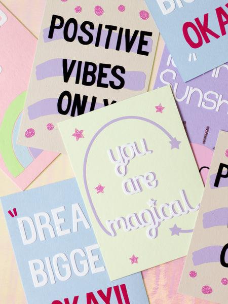 A selection of colourful art prints overlapping each other. Each with a different affirmational quote.