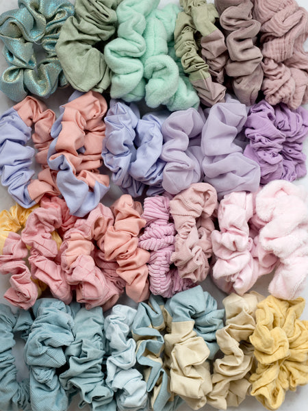 Four rows of neatly lined up scrunchies in a rainbow of colours and textures.