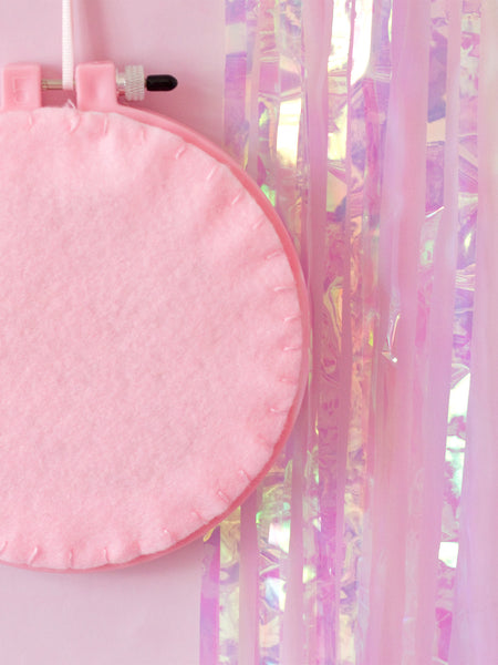 The back of a pink embroidery hoop shows the felted closure.