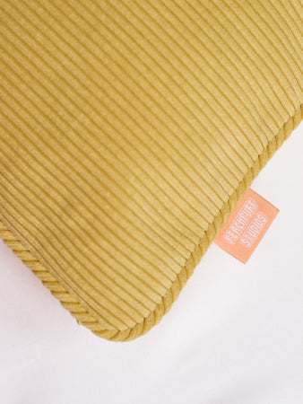 A close-up of a yellow corduroy cushion cover to show the pipping and ribbed details.