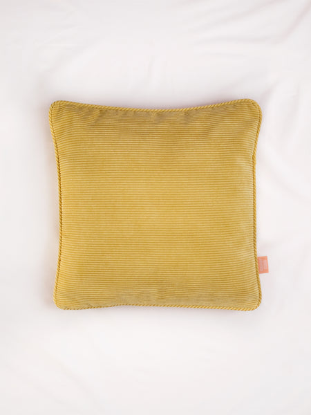 A yellow corduroy cushion on the centre of a white bedsheet 
