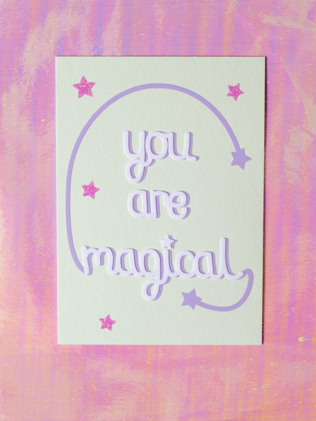 Art print with You Are Magical in flocked font with a purple curved line with a star at the end, coming off with M and L of magical. 